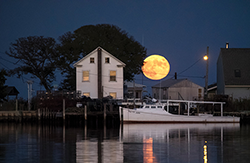 A blood moon rises over a waterman’s home and workboat on Smith Island. Photograph courtesy of David Harp